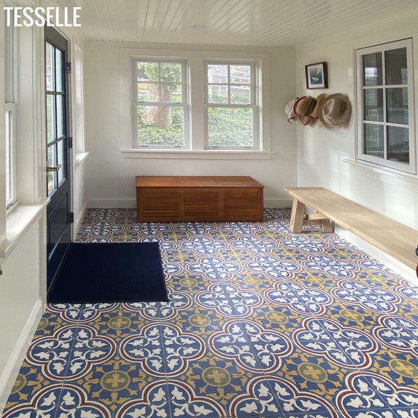 Foyer with patterned Lyssa Alsace floor tiles, wooden bench, and storage chest.